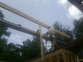 Carpenter setting a ridge beam over a new addition frame — Ice Dam Removal by Roofing Brothers in Holly Ridge