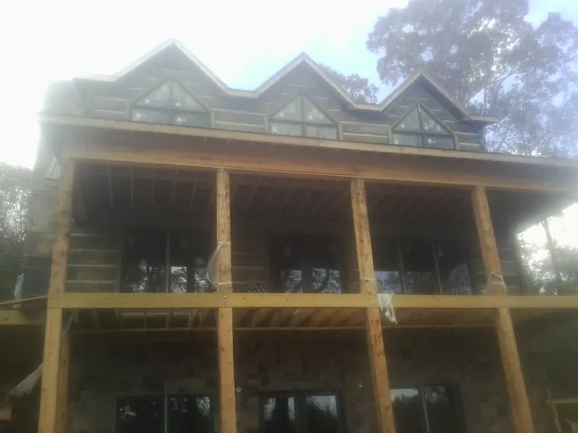 Dormers and porch framing on a large log home under construction — Roof Coating work by our crew in Holly Ridge